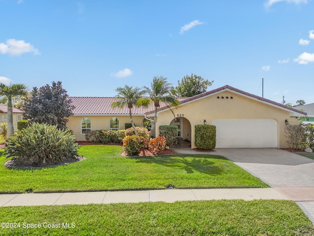 mediterranean / spanish-style house featuring a front yard and a garage