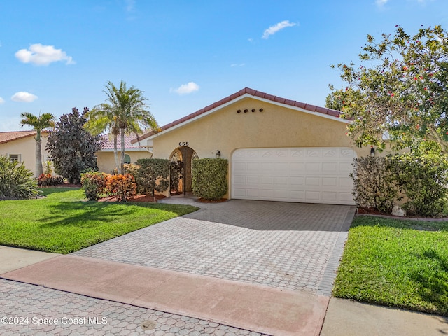 mediterranean / spanish house featuring a garage and a front lawn