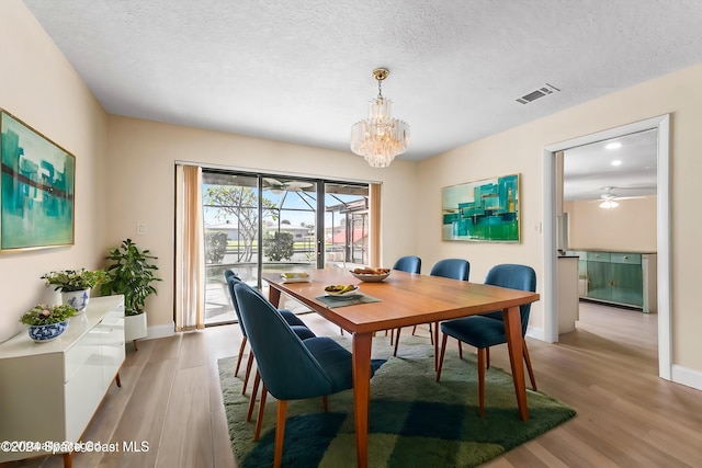 dining area with a chandelier, light hardwood / wood-style flooring, and a textured ceiling