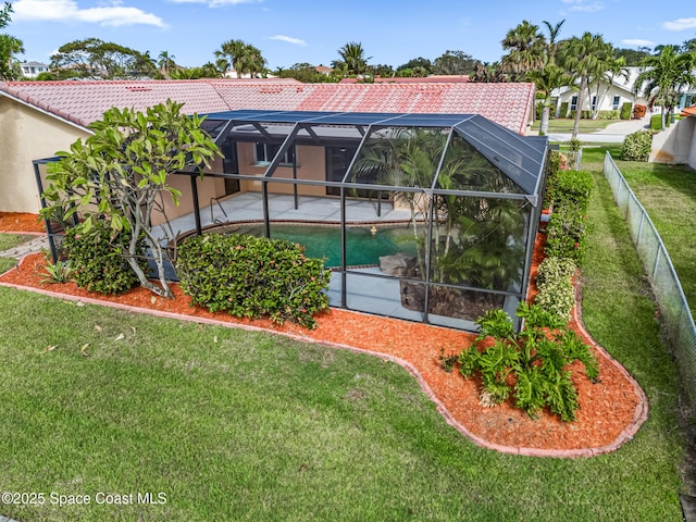 back of property with a patio area, a lawn, and glass enclosure