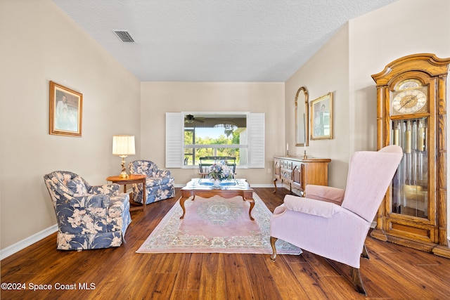 living area with a textured ceiling, dark hardwood / wood-style floors, and ceiling fan