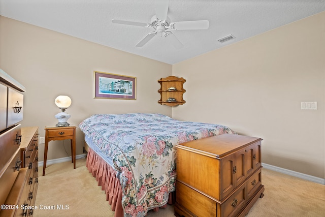 carpeted bedroom featuring ceiling fan and a textured ceiling