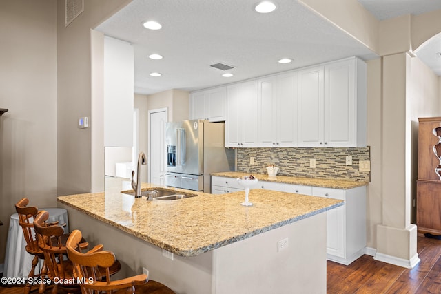 kitchen with high end fridge, sink, white cabinets, light stone counters, and dark hardwood / wood-style flooring