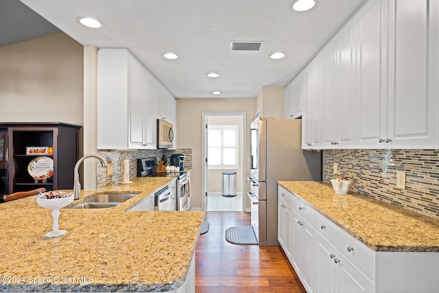 kitchen featuring dark hardwood / wood-style floors, stainless steel appliances, sink, white cabinets, and tasteful backsplash