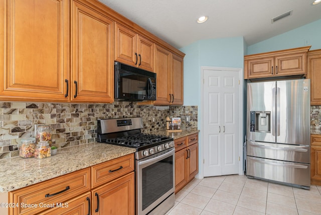 kitchen featuring decorative backsplash, light stone counters, stainless steel appliances, light tile patterned floors, and lofted ceiling