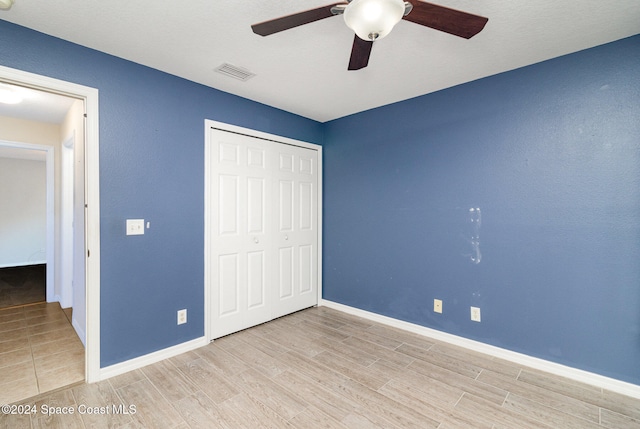 unfurnished bedroom featuring ceiling fan, light hardwood / wood-style flooring, and a closet