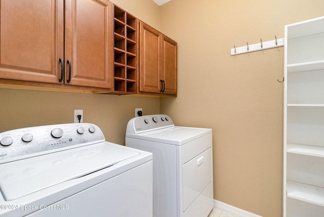 laundry area featuring cabinets, light tile patterned floors, and washer and clothes dryer