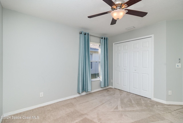 unfurnished bedroom with ceiling fan, light colored carpet, a textured ceiling, and a closet