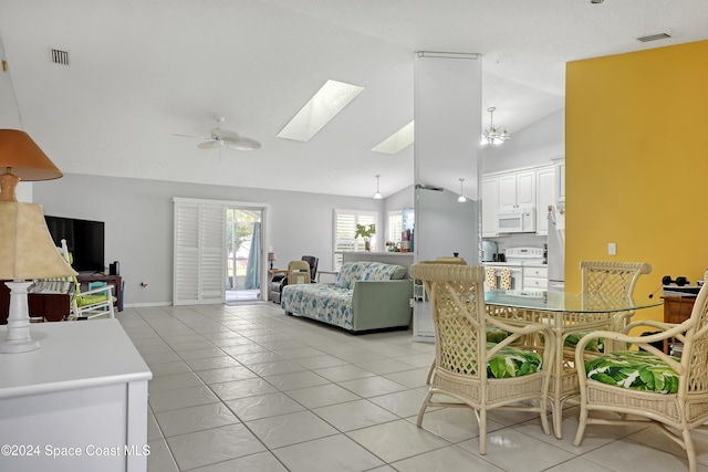 dining area featuring lofted ceiling with skylight, light tile patterned floors, and ceiling fan with notable chandelier