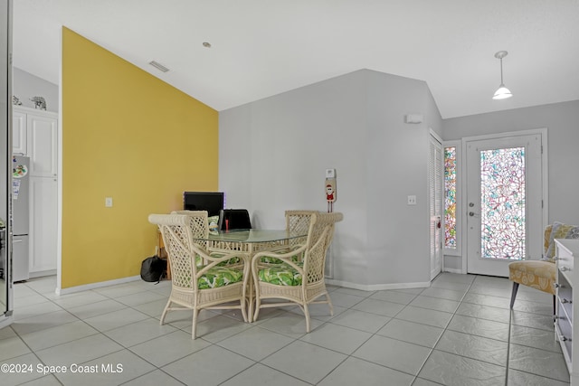 tiled dining room featuring vaulted ceiling