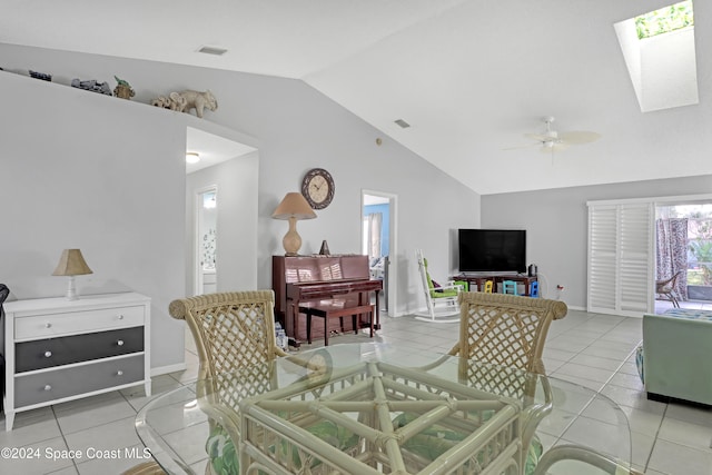 living room with ceiling fan, light tile patterned floors, and lofted ceiling with skylight