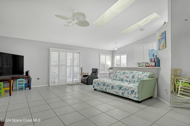 living room featuring light tile patterned floors, lofted ceiling with skylight, and ceiling fan