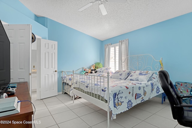 bedroom with a textured ceiling, light tile patterned floors, and ceiling fan