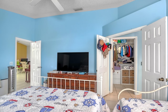 tiled bedroom with ceiling fan, a textured ceiling, and a closet