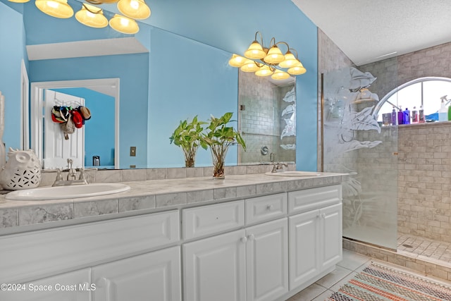 bathroom featuring vanity, a textured ceiling, tile patterned flooring, and a tile shower