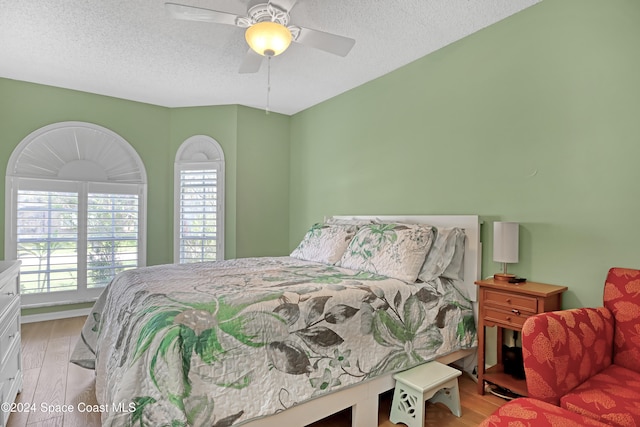 bedroom featuring light hardwood / wood-style floors, a textured ceiling, and ceiling fan