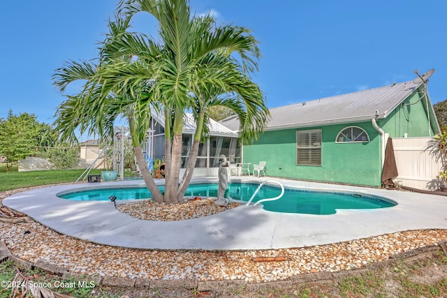 view of pool with a sunroom and a patio area