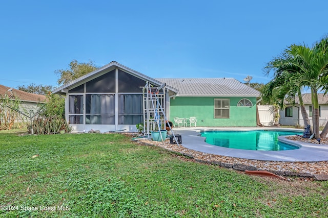 rear view of property with a patio area, a sunroom, and a lawn