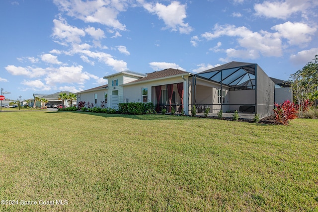 rear view of house with a lanai and a lawn