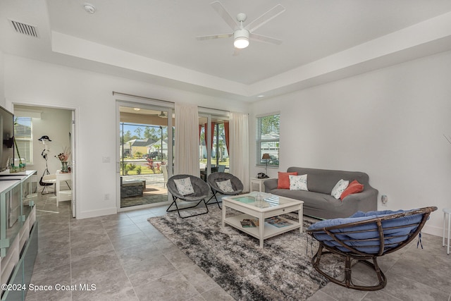 living room with a tray ceiling and ceiling fan