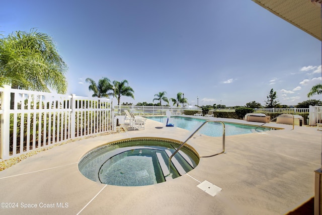 pool featuring fence, a community hot tub, and a patio area