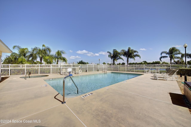 community pool with fence, a patio, and a community hot tub