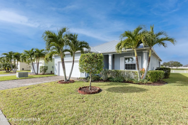 ranch-style house with driveway, metal roof, a front yard, a garage, and stucco siding