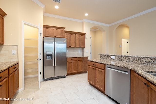 kitchen featuring crown molding, decorative backsplash, stainless steel appliances, and brown cabinets