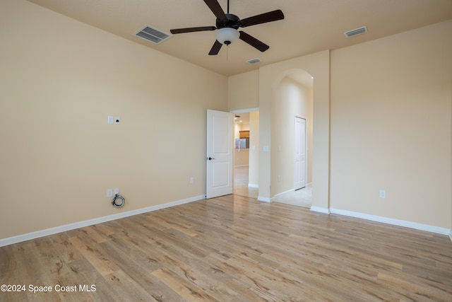 spare room with visible vents, arched walkways, light wood-style floors, and ceiling fan