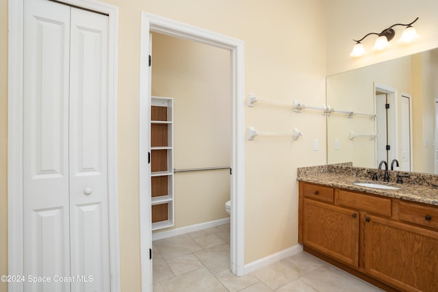bathroom with tile patterned flooring, vanity, baseboards, a closet, and toilet