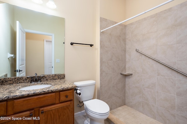 bathroom featuring toilet, a tile shower, and vanity