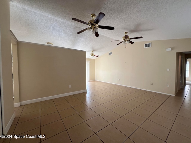 unfurnished room with a textured ceiling, tile patterned floors, and lofted ceiling