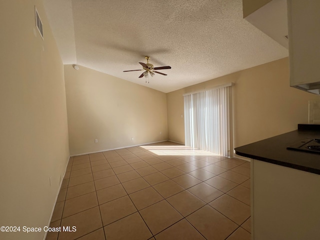 unfurnished living room featuring vaulted ceiling, ceiling fan, light tile patterned floors, and a textured ceiling