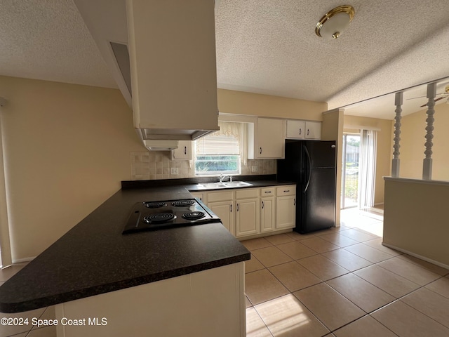 kitchen with white cabinets, black fridge, a textured ceiling, tasteful backsplash, and kitchen peninsula