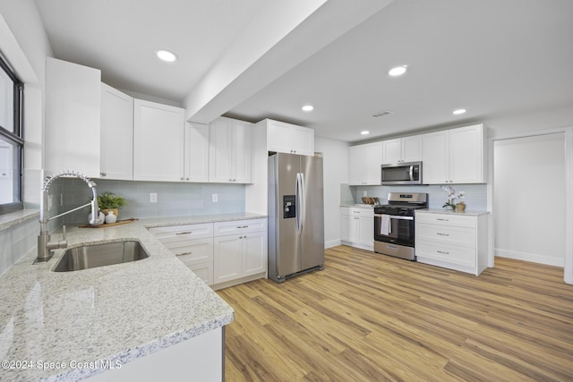 750 W Whitmire Dr, Melbourne, FL 32935 - kitchen featuring stainless steel appliances, a sink, light stone countertops, light wood-type flooring, and backsplash