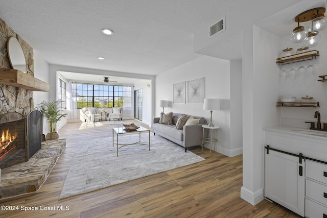 750 W Whitmire Dr, Melbourne, FL 32935 - living room with baseboards, a textured ceiling, a stone fireplace, wood finished floors, and recessed lighting
