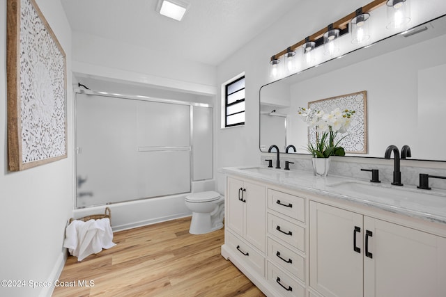 full bathroom with toilet, vanity, hardwood / wood-style flooring, and combined bath / shower with glass door