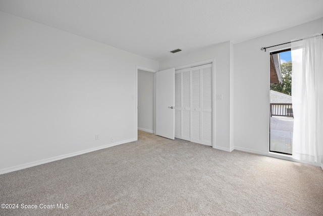 unfurnished bedroom with light colored carpet and a closet