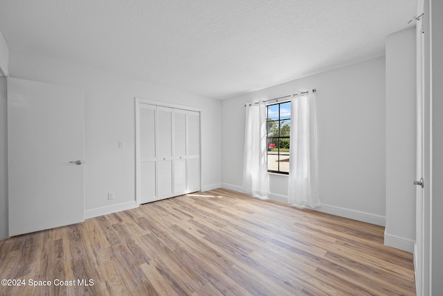 unfurnished bedroom with light hardwood / wood-style floors and a textured ceiling