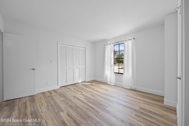 750 W Whitmire Dr, Melbourne, FL 32935 - unfurnished bedroom with light wood-style floors, a closet, baseboards, and a textured ceiling