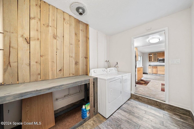 clothes washing area with wood-type flooring, a textured ceiling, and washing machine and clothes dryer