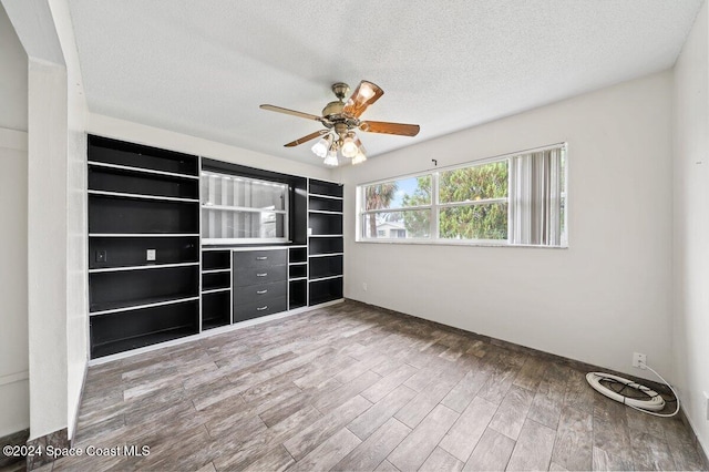 unfurnished bedroom with ceiling fan, wood-type flooring, and a textured ceiling