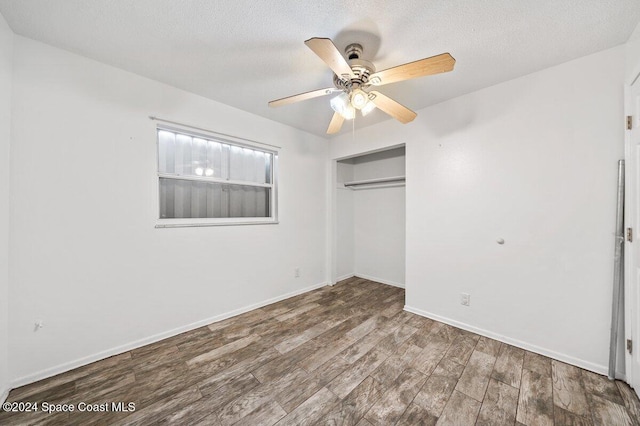 unfurnished bedroom with ceiling fan, a closet, a textured ceiling, and hardwood / wood-style flooring