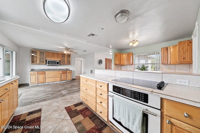 kitchen with ceiling fan, light hardwood / wood-style floors, decorative backsplash, and appliances with stainless steel finishes