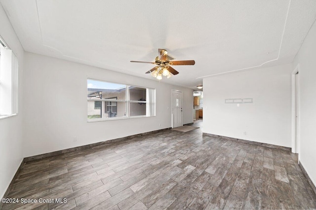 unfurnished living room with ceiling fan and dark wood-type flooring