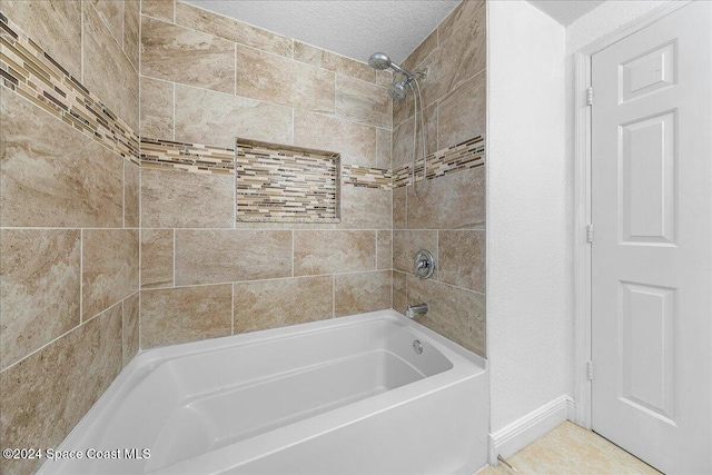 bathroom with tiled shower / bath combo and a textured ceiling