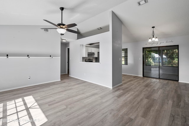 unfurnished living room featuring lofted ceiling, hardwood / wood-style floors, a textured ceiling, and ceiling fan with notable chandelier