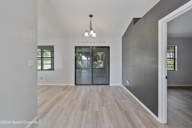 foyer featuring a notable chandelier, a textured ceiling, and light wood-type flooring