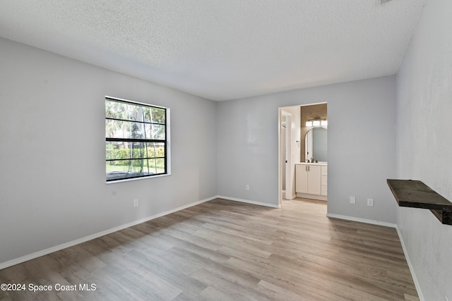 empty room featuring a textured ceiling and light wood-type flooring