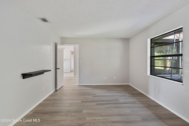 unfurnished room featuring light hardwood / wood-style floors and a textured ceiling